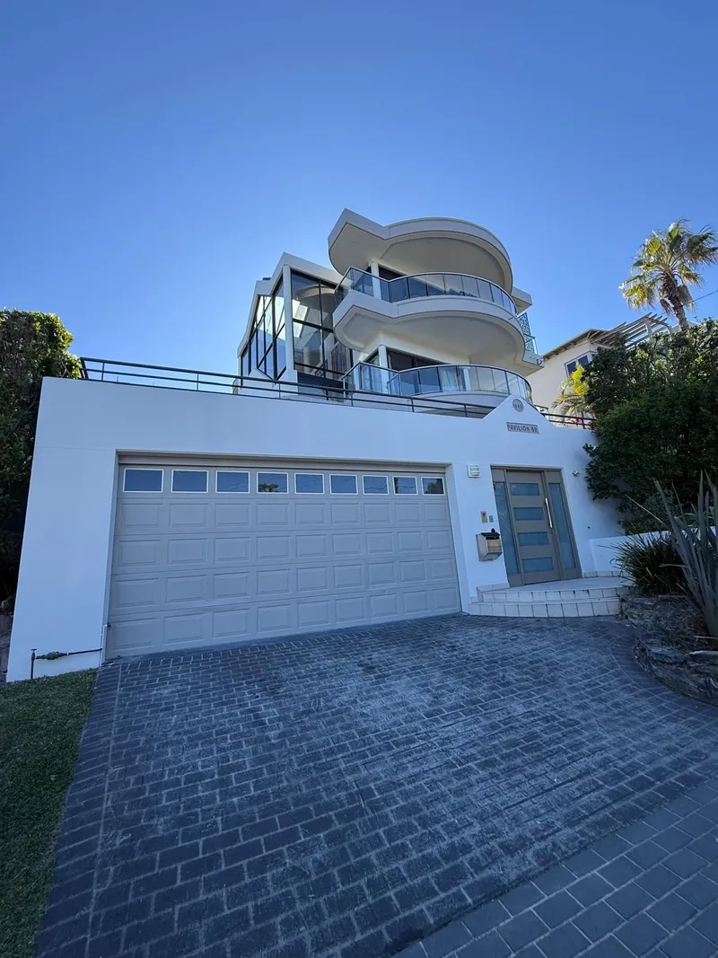 Front of a white rendered home with a curved balcony and double garage