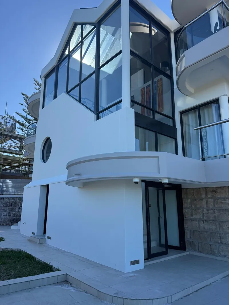 White render facade with a round porthole window and glass stairwell