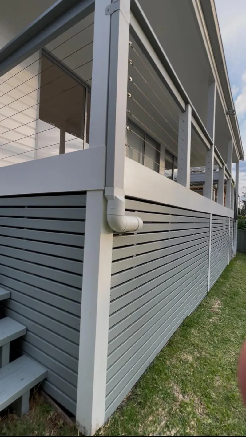 Painted batten screen and deck framing under a balcony