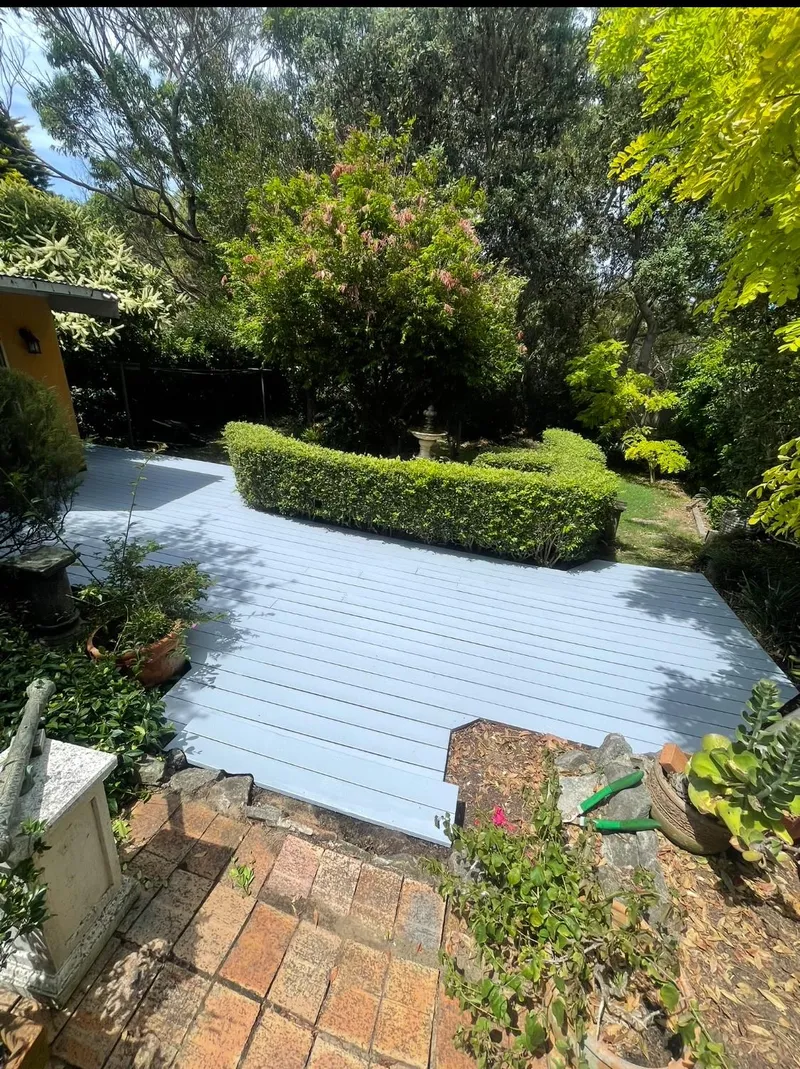 Garden deck coated in pale blue-grey surrounded by hedges