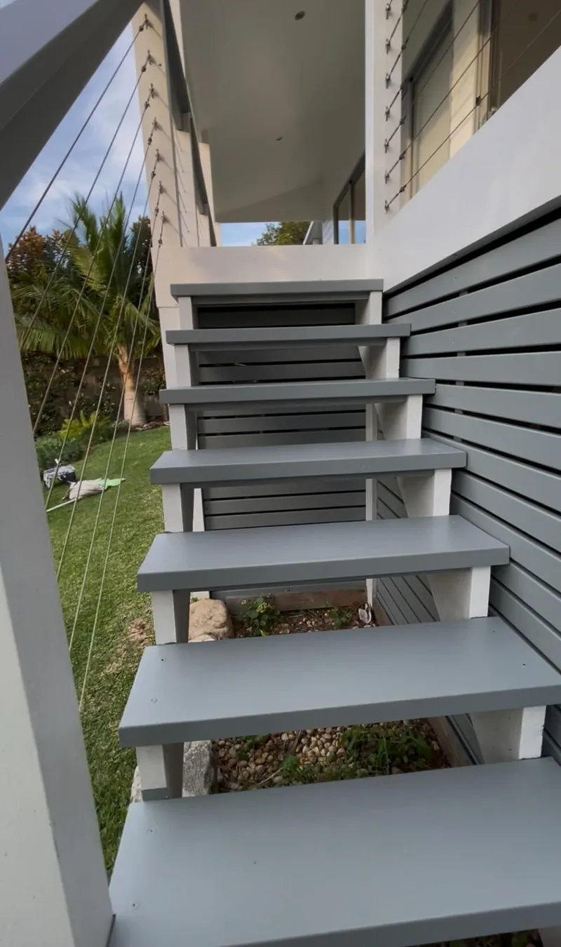 Painted timber stairs leading down from a deck to the garden