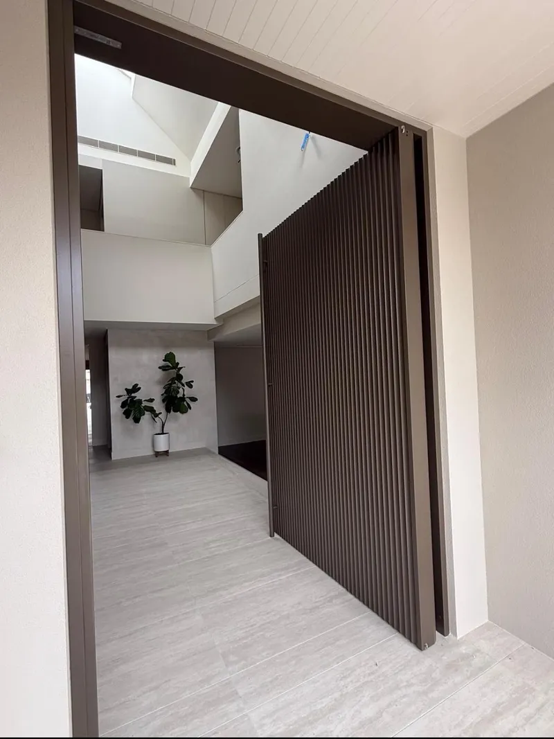 Tall pivot entry door opening into a bright painted hallway